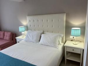 阿齐欧斯·贡多斯Agios Gordios Boutique Resort的卧室配有一张白色床、两张桌子和两盏灯。