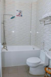 莲三Hoang My Hotel Phú Yên的浴室配有白色浴缸、卫生间和水槽。
