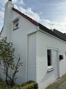 GraauwHeerlijk Dijkhuisje in Paal的白色的房子,有窗户和屋顶