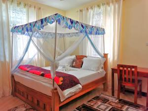 Chaki ChakiSinthia Hotel Apartments的一间卧室配有一张天蓬床和一张桌子