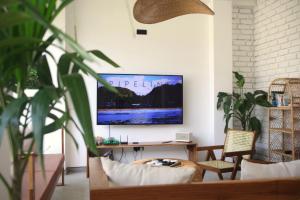 韦利格默OASIA - Boutique Surf House (ADULTS ONLY)的客厅配有书桌和墙上的电视