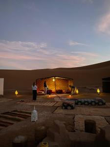 姆哈米德Chigaga Desert Camp的两个人站在沙漠中的一座建筑物前