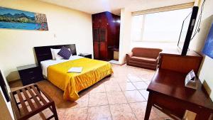 帕斯托Hotel Xilon Resort Plaza的一间卧室配有一张床、一张桌子和一把椅子