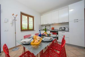 拉韦诺-蒙贝洛Le Betulle Garden in Laveno的一间带红色椅子的桌子的厨房和一间带白色橱柜的厨房