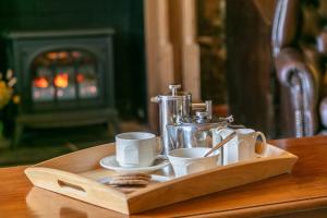 哈佛威斯特东方胡克农舍旅馆的一张带杯子的木制托盘和一张桌子上的咖啡壶