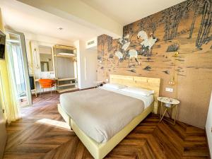 代森扎诺-德尔加达维托里奥酒店的卧室配有一张大床,墙上挂着壁画