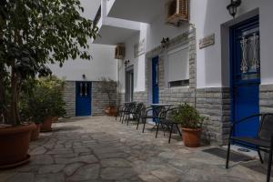 提诺斯Soula Rooms Tinos的庭院配有椅子和桌子,设有蓝色的门