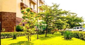 阿布贾Sandralia Hotel的一座花园,在一座建筑前种有树木和植物