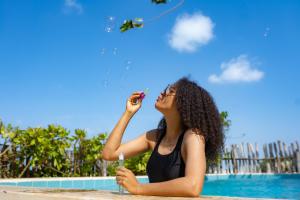 江比阿Pili Pili Uhuru Beach Hotel的一名妇女在游泳池边放风筝