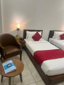AlleppeyHotel Abaam Neil的酒店客房,配有两张床、椅子和桌子