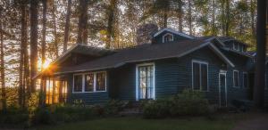 Paul SmithsWhite Pine Camp的阳光照耀着树丛的小房子
