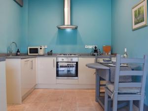 Llangwm-isafTy Ffair Mai Annexe的厨房配有白色橱柜和蓝色的墙壁