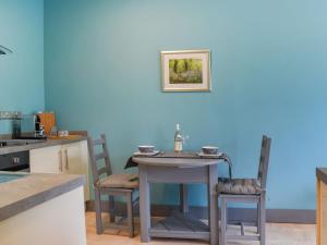 Llangwm-isafTy Ffair Mai Annexe的厨房里设有一张桌子和椅子,拥有蓝色的墙壁