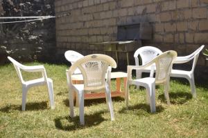 KiambuMella homes limuru的坐在烤架前的草地上四把白色椅子