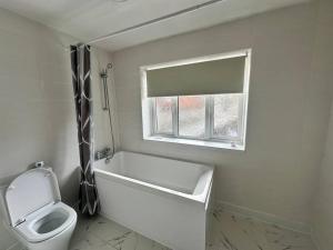 特伦特河畔斯托克Sage House - City centre Hanley, Alton towers的带浴缸、卫生间和窗户的浴室