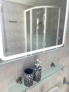 诺德克豪特Beach Bungalow - Noordwijk aan Zee的浴室内的一个镜子和两个杯子放在架子上