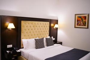 拉合尔Faletti’s Grand MM Alam Road的一间卧室配有一张大床和大床头板