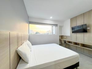 蒙特里亚Stanza Hotel Monteria的卧室配有白色的床和平面电视。