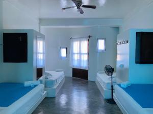 曼克拉Loki del Mar的蓝色客房配有两张床和风扇