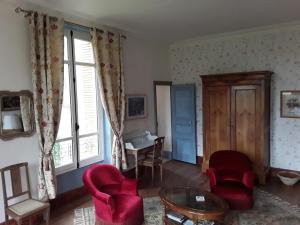 维莱讷-拉瑞埃勒Le Chateau du grand Coudray的客厅配有红色椅子和桌子