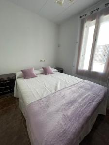 BenifalletLo Jardí de Benifallet的白色卧室配有带粉红色枕头的大床