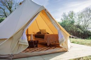 坡隆维茨普尔扎伊The Glamping Spot - Douarnenez的黄帐篷,田野里有一张床