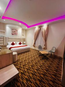 Al Fayşalīyahشقق الروشن الجوفي的酒店客房,配有一张床和紫色照明