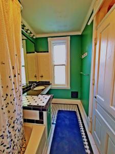 匹兹堡Point Breeze Guest House的浴室设有绿色的墙壁、水槽和窗户。