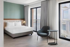 哥本哈根Fairfield by Marriott Copenhagen Nordhavn的酒店客房带一张床、椅子和窗户
