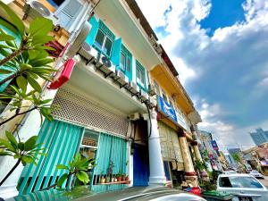 马六甲Melaka jonker street kids friendly guesthouse Malacca的一座带蓝色百叶窗的建筑,一条街道上停有一辆汽车