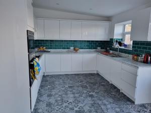 LlannonNo.11的厨房配有白色橱柜和瓷砖地板。