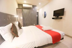 卡延Hotel Leesha Residency的卧室配有一张大床,墙上配有电视