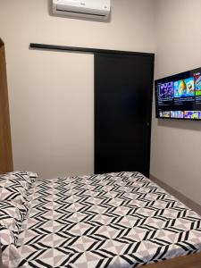 普鲁登特总统城Studios Soho Bongiovani的卧室配有一张床,墙上配有电视。