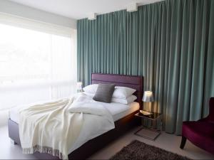 洛桑VISIONAPARTMENTS Rue Caroline - contactless check-in的一间卧室配有一张带绿色窗帘的床和窗户。