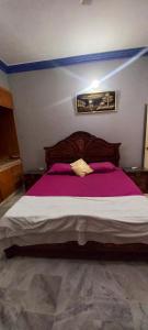 卡拉奇Maymar Holiday Home的一间卧室配有一张带紫色床单的大床