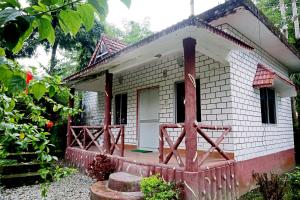 JalpāiguriAyush Jungle Resort的一座白色的小砖房子,设有木门