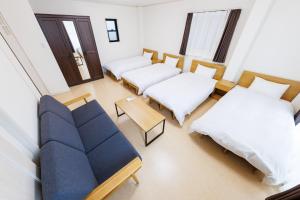 大阪5 minutes Shin-Osaka 3的客房设有两张床、一张沙发和一张桌子。