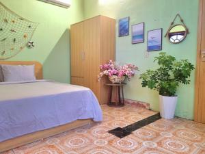 洞海Blue Sea House Quảng Bình - Căn hộ 2 phòng ngủ, phòng khách và phòng bếp的卧室配有一张床,墙上挂着鲜花