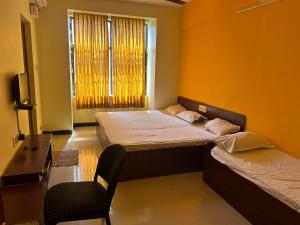 哥印拜陀Aishvarya Residency Coimbatore的一间卧室设有两张床、一把椅子和一个窗户。
