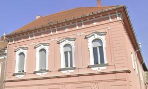 陶波尔曹Classic Deluxe Tapolca的粉红色的建筑,上面有白色的窗户
