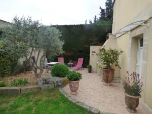 博凯尔Chambre d'Hôtes entre Provence et Camargue的庭院配有粉红色的椅子和桌子,树木繁茂