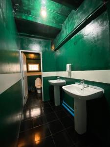 芭堤雅市中心Happiness Community Wake & Bake Hostel - Rooftop Bar & Bistro的绿色浴室设有两个盥洗盆和卫生间