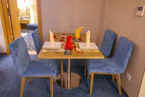 欧奈宰Cheerful Al Waha Hotel Unayzah - فندق شيرفل عنيزة的一张桌子,房间内设有蓝色的椅子和一张带蜡烛的桌子