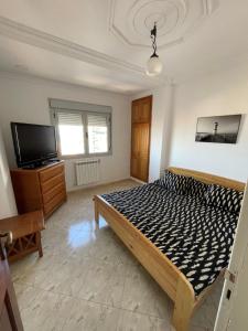Mostaganembel appart mosta的一间卧室配有一张床和一台平面电视