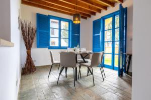 波利斯The Olympians Villas的一间设有蓝色窗户和桌椅的用餐室