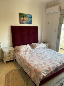 Mostaganembel appart mosta的一间卧室配有一张大床和红色床头板