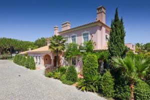 韦尔都勒博Quinta Jacintina - My Secret Garden Hotel的一座大粉红色的房子,有树木和灌木