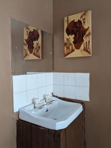 Stone TownFlamingo Guest House ZNZ的一间带水槽的浴室和墙上的两张照片