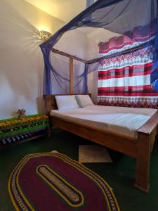 Stone TownFlamingo Guest House ZNZ的一间卧室配有一张天蓬床和地毯。