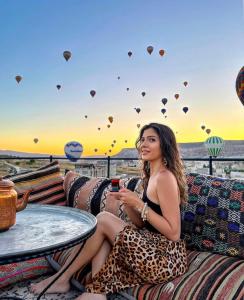 格雷梅Garden Suites Hotel Cappadocia的坐在沙发上看热气球的女人